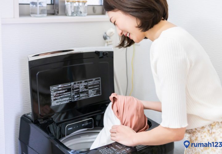 perempuan mencuci dengan mesin cuci top loading